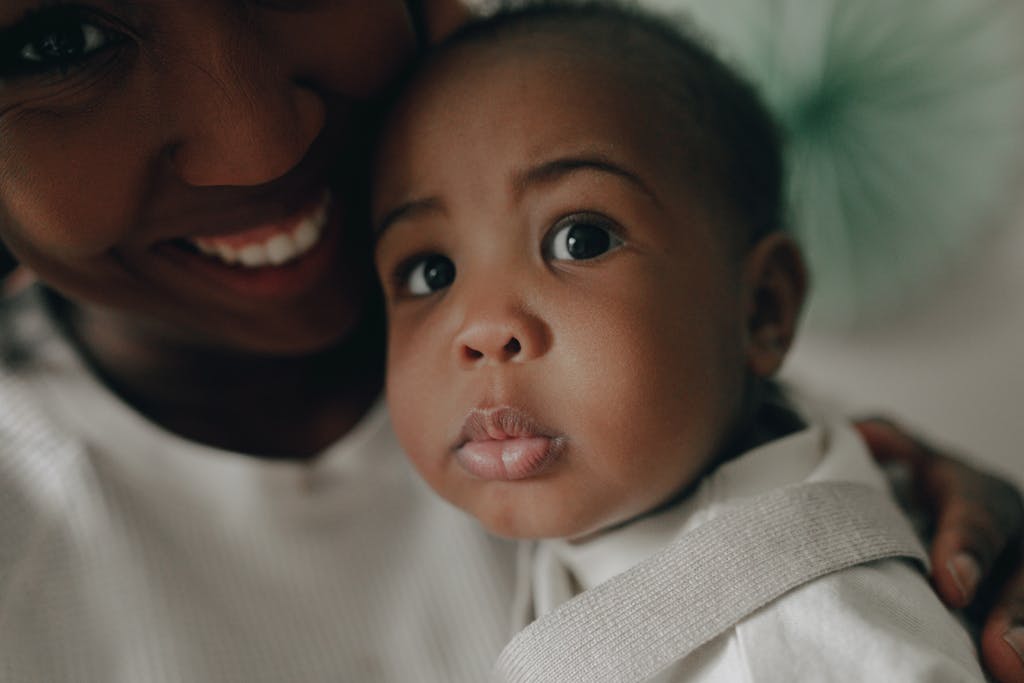 African American mother lovingly holds her baby, showcasing a close-up of faces filled with tenderness.