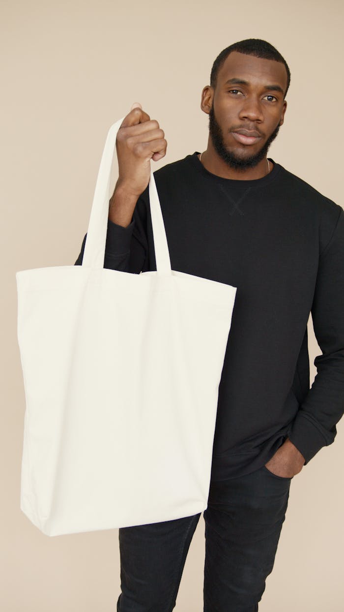 How Pendo Bridging Care Keeps Your Family Close When You’re Far Away Portrait of a young man holding a blank white tote bag, ideal for mockup and branding purposes.