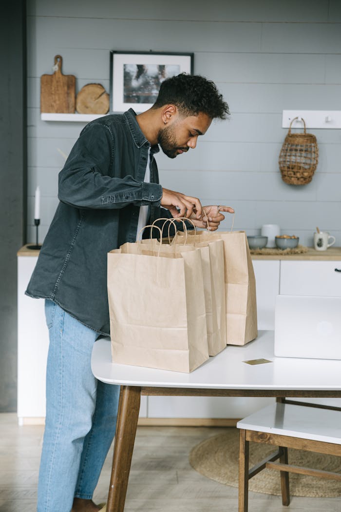 Safeguarding Your Property in Kenya While You Live Abroad Young man organizing paper shopping bags indoors in a modern kitchen setting.